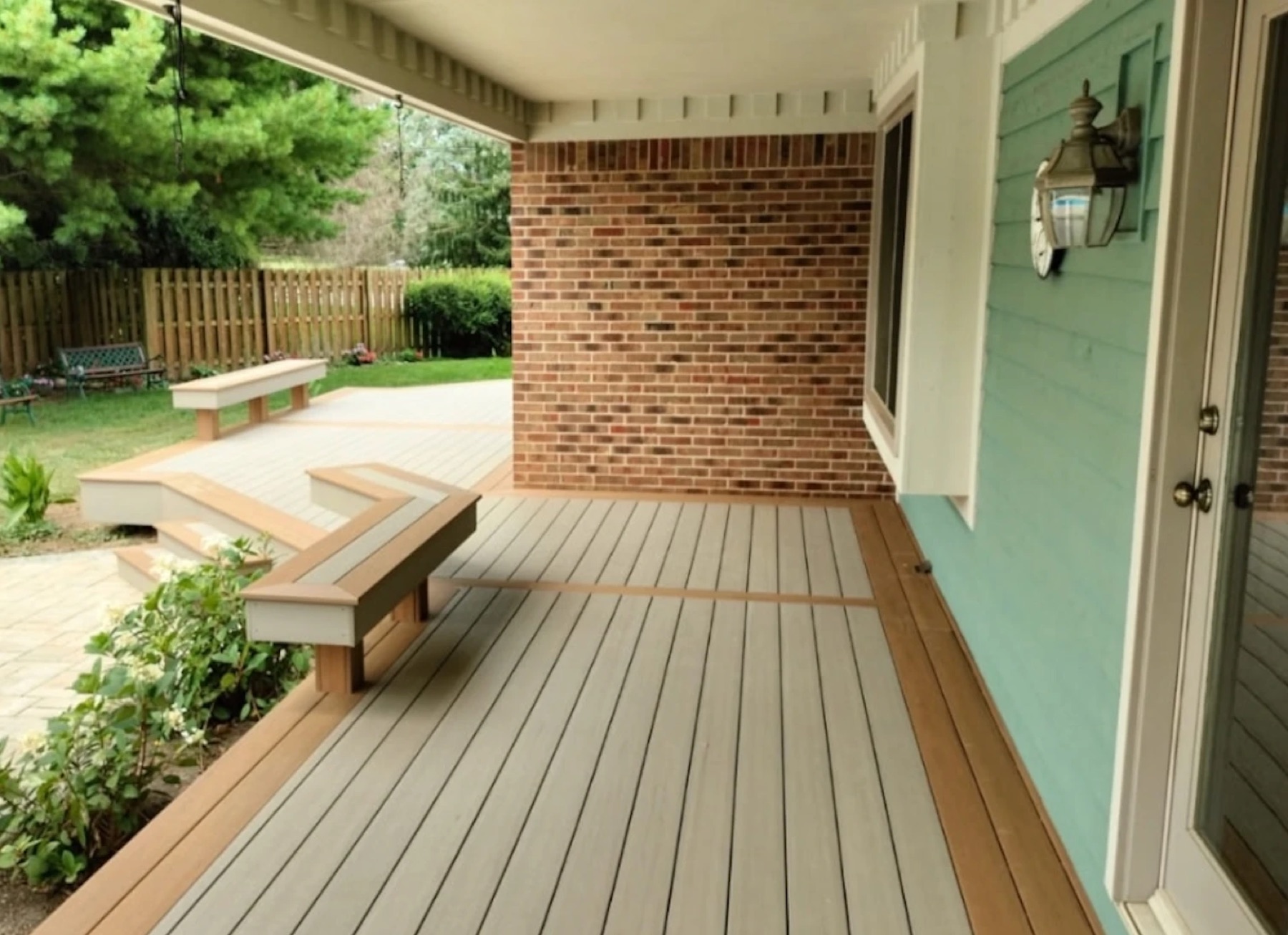 Grey composite covered porch with a tan border running out to an open deck with built-in benches