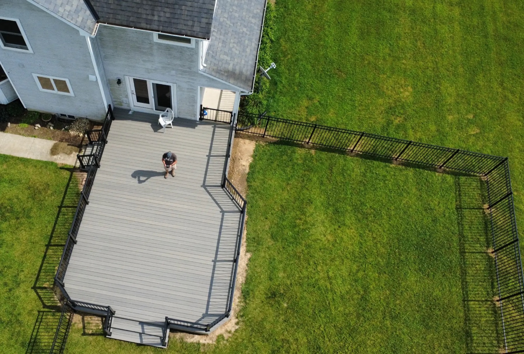 Aerial view of a large grey composite deck with black aluminum railing behind a two-story home