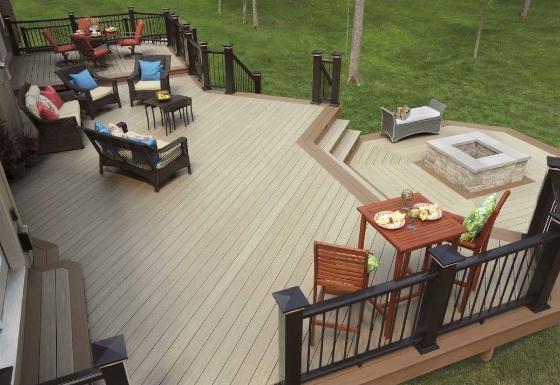 Light composite deck with seating areas, black railing and steps down to a framed fire-pit level